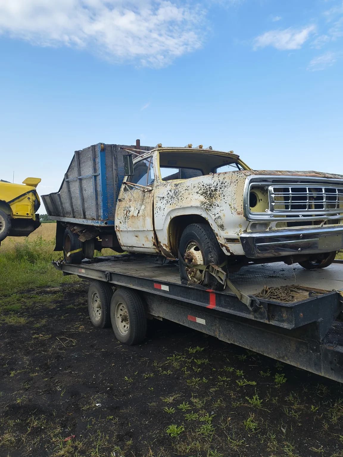 Older Dodge medium-duty dump truck secured on a flatdeck trailer