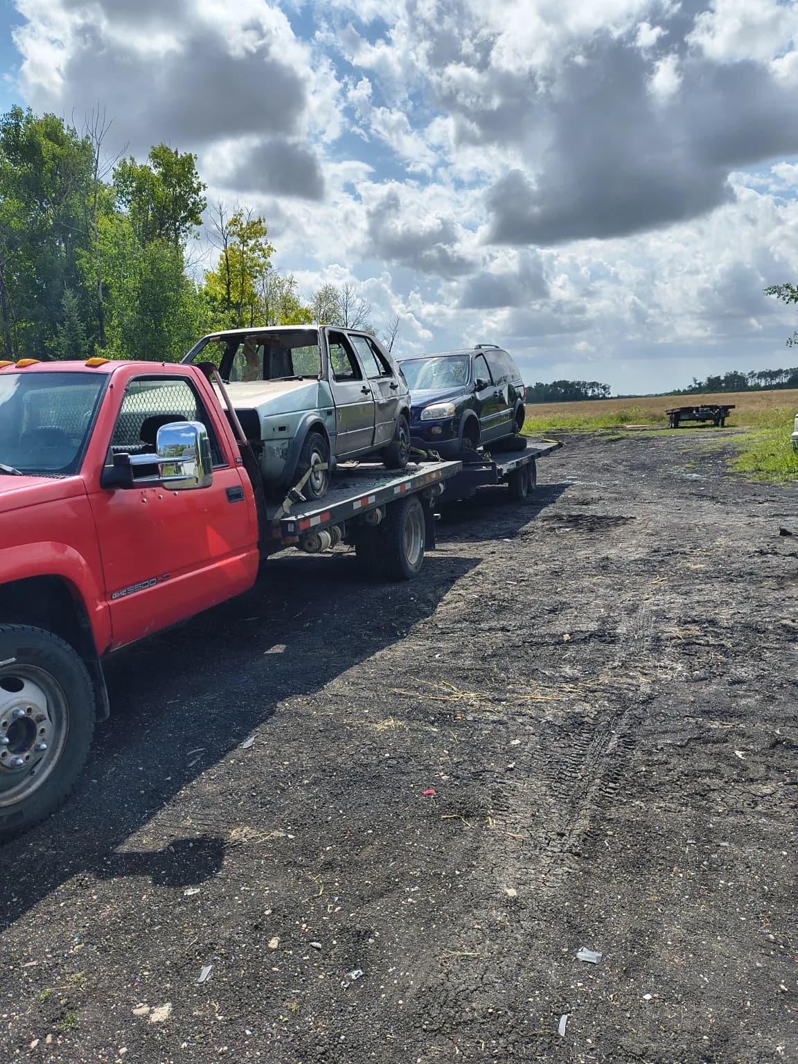 Two non-running vehicles secured on a Recycle Your Ride flatdeck for pickup