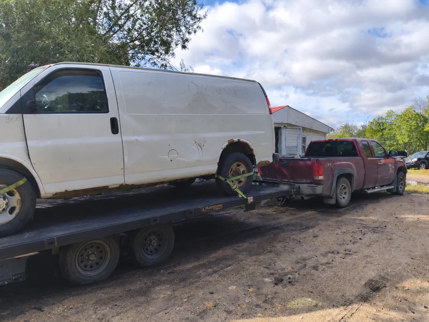 White full-size cargo van secured on a trailer for pickup in Manitoba